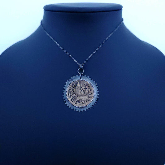Unique pendant featuring a vintage bronze button with an intricately designed heron amid blooming flowers, set in a handcrafted sterling silver frame with a delicate floral motif.