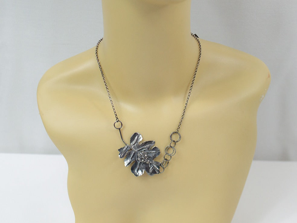 Handcrafted sterling silver pendant featuring a meticulously detailed ladybug resting on a textured, lifelike leaf. The design showcases expert metalwork, including fusing, reticulation, and soldering, finished with oxidation and polishing for depth and contrast. Paired with a handcrafted silver chain for a unique touch.
