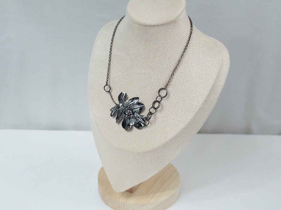 Handcrafted sterling silver pendant featuring a meticulously detailed ladybug resting on a textured, lifelike leaf. The design showcases expert metalwork, including fusing, reticulation, and soldering, finished with oxidation and polishing for depth and contrast. Paired with a handcrafted silver chain for a unique touch.