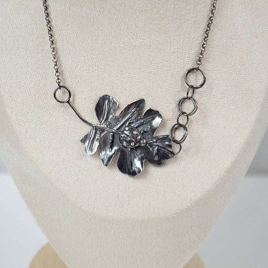 Handcrafted sterling silver pendant featuring a meticulously detailed ladybug resting on a textured, lifelike leaf. The design showcases expert metalwork, including fusing, reticulation, and soldering, finished with oxidation and polishing for depth and contrast. Paired with a handcrafted silver chain for a unique touch.