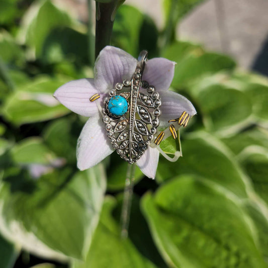 Sterling silver leaf pendant featuring a vibrant turquoise stone, capturing the beauty of nature with intricate detailing and striking color. A unique accessory perfect for nature lovers.