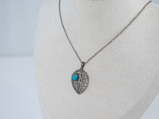 Sterling silver leaf pendant featuring a vibrant turquoise stone, capturing the beauty of nature with intricate detailing and striking color. A unique accessory perfect for nature lovers.