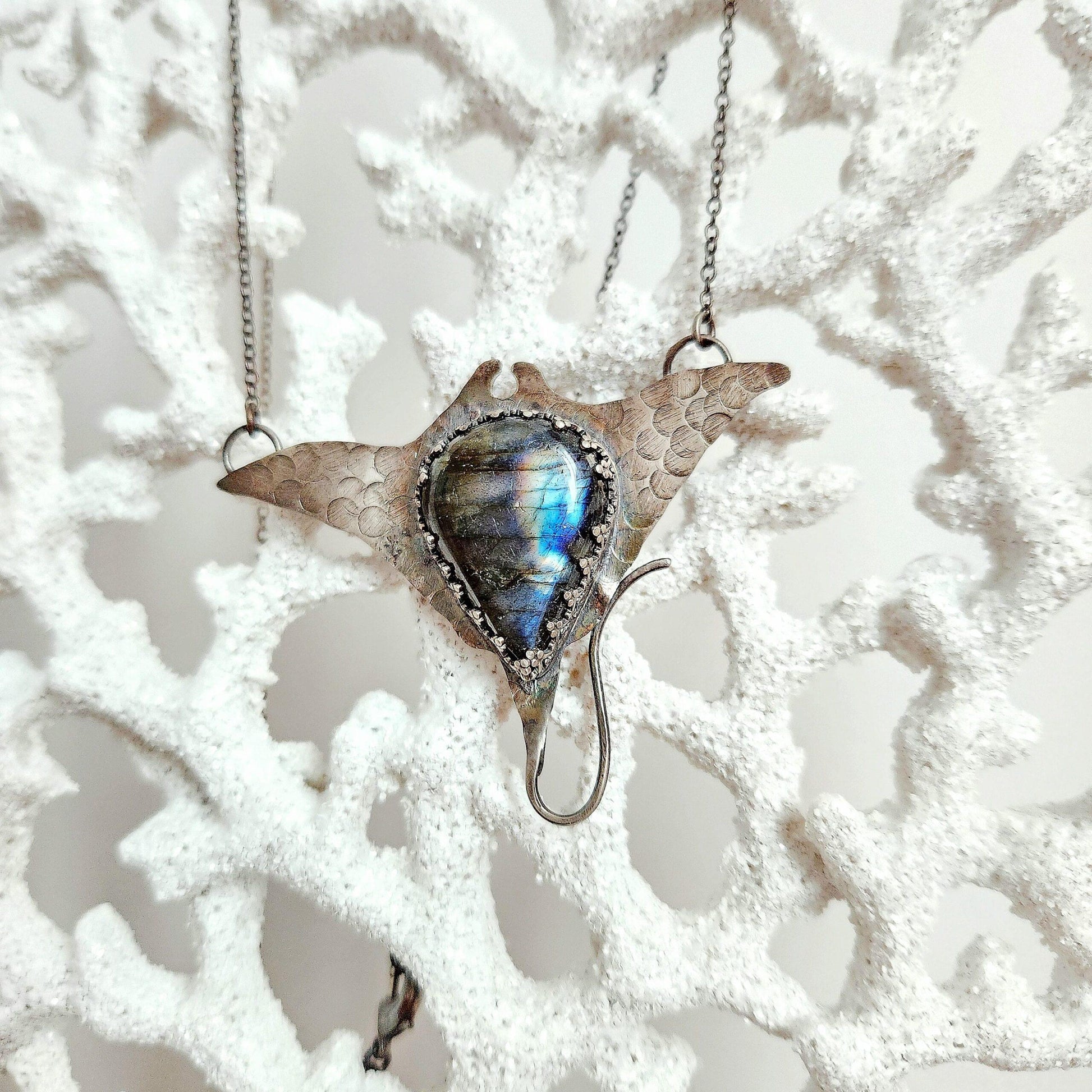 Labradorite pendant sculpted into the fluid form of a graceful manta ray, shimmering with iridescent hues. A striking statement piece symbolizing wisdom and effortless elegance.