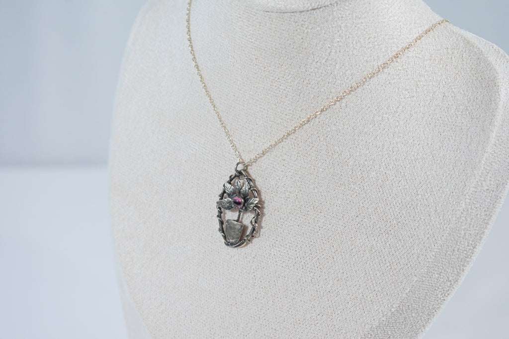 Elegant miniature leaf pendant necklace featuring a deep red garnet stone, crafted in sterling silver.