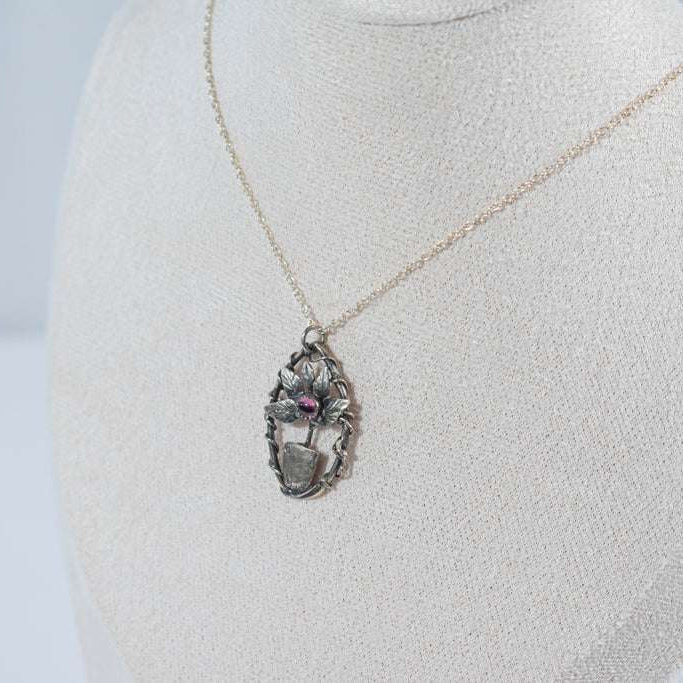 Elegant miniature leaf pendant necklace featuring a deep red garnet stone, crafted in sterling silver.
