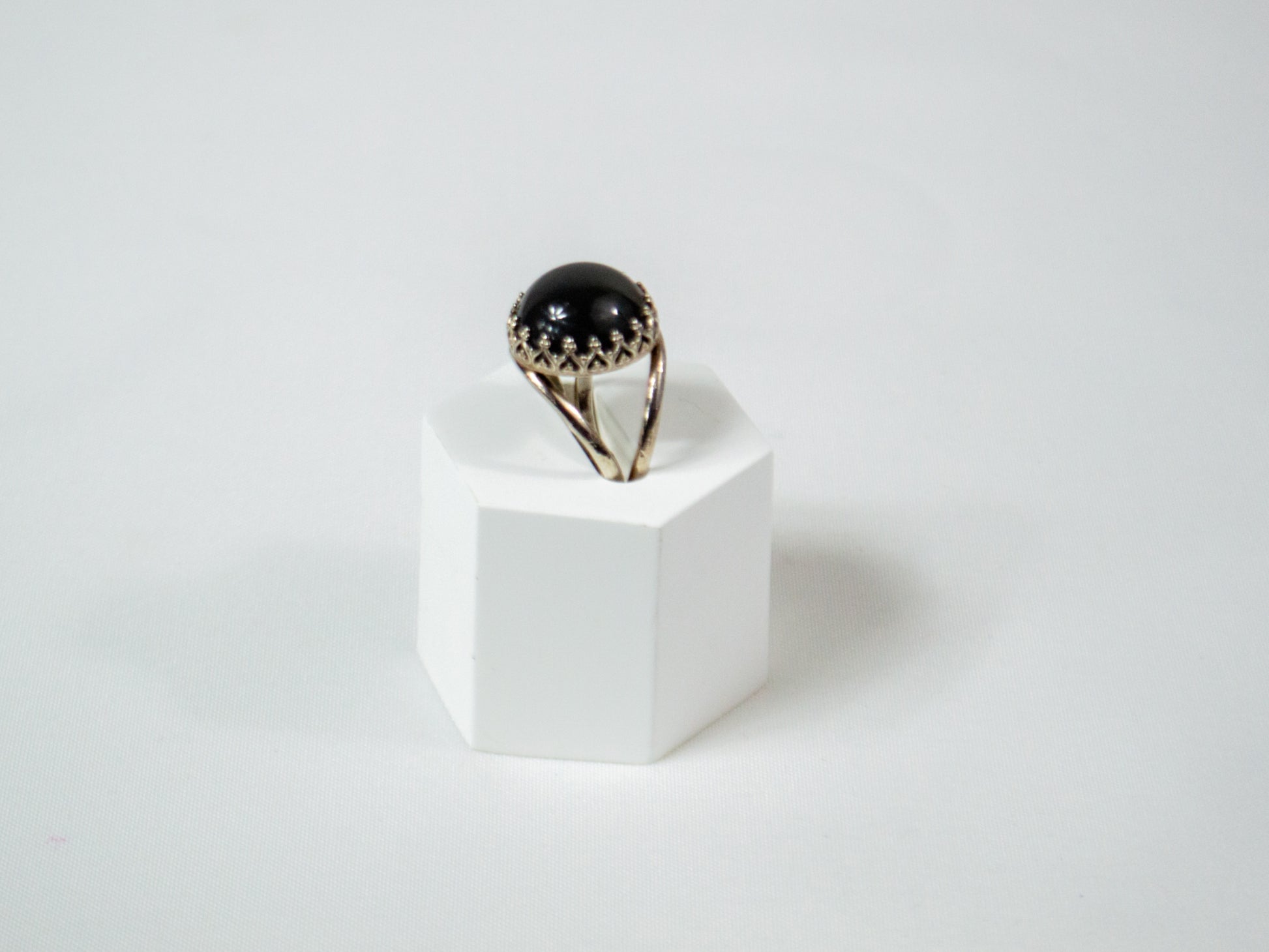 A delicate handcrafted sterling silver ring featuring a 14mm Grey Moonstone cabochon in a crown bezel setting, radiating a soft, ethereal glow.