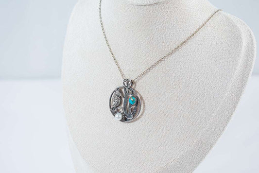 A delicate silver circle necklace featuring a finely detailed seahorse, a vibrant turquoise stone reminiscent of the ocean, and a luminous pearl. A handcrafted treasure that captures the spirit of the sea.
