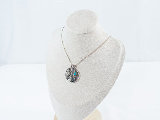 A delicate silver circle necklace featuring a finely detailed seahorse, a vibrant turquoise stone reminiscent of the ocean, and a luminous pearl. A handcrafted treasure that captures the spirit of the sea.