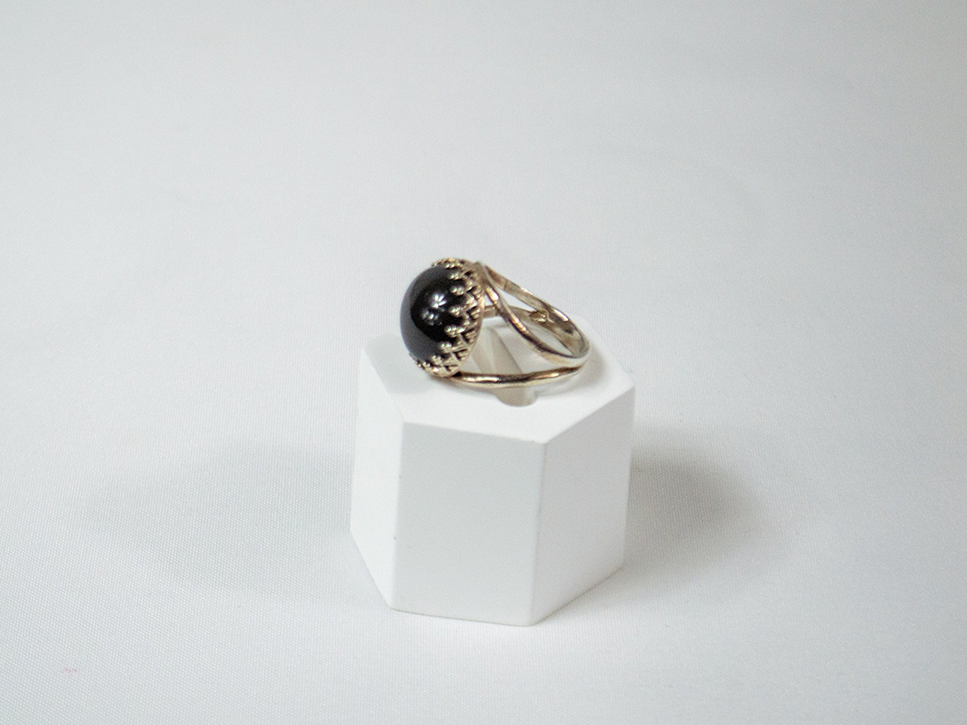 A delicate handcrafted sterling silver ring featuring a 14mm Grey Moonstone cabochon in a crown bezel setting, radiating a soft, ethereal glow.