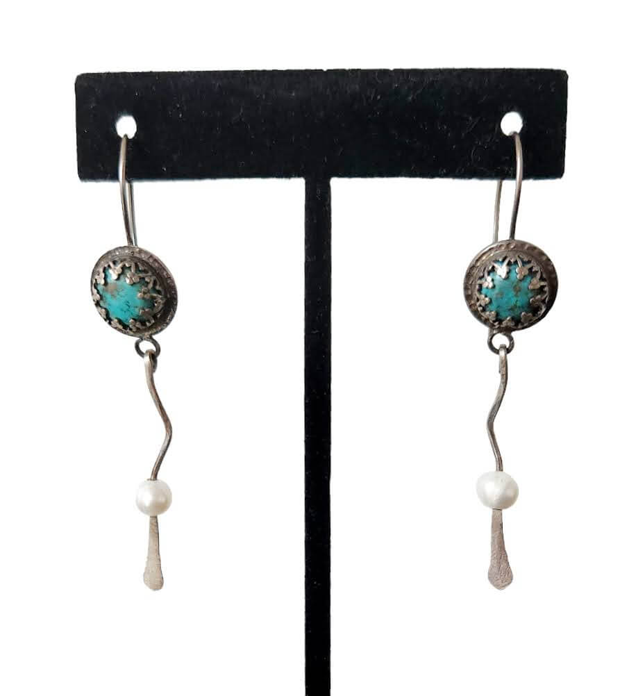 A pair of silver and turquoise dangle earrings with wavy silver accents, gracefully ending in smooth freshwater pearls for a balanced and elegant design