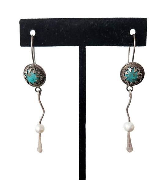 A pair of silver and turquoise dangle earrings with wavy silver accents, gracefully ending in smooth freshwater pearls for a balanced and elegant design