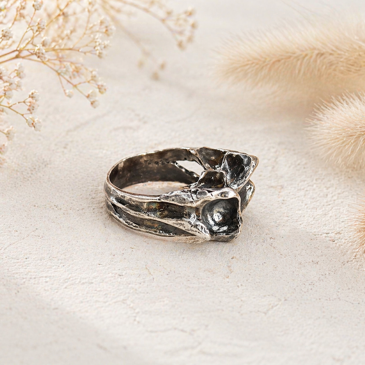 Silver ring with textured design on a light beige background