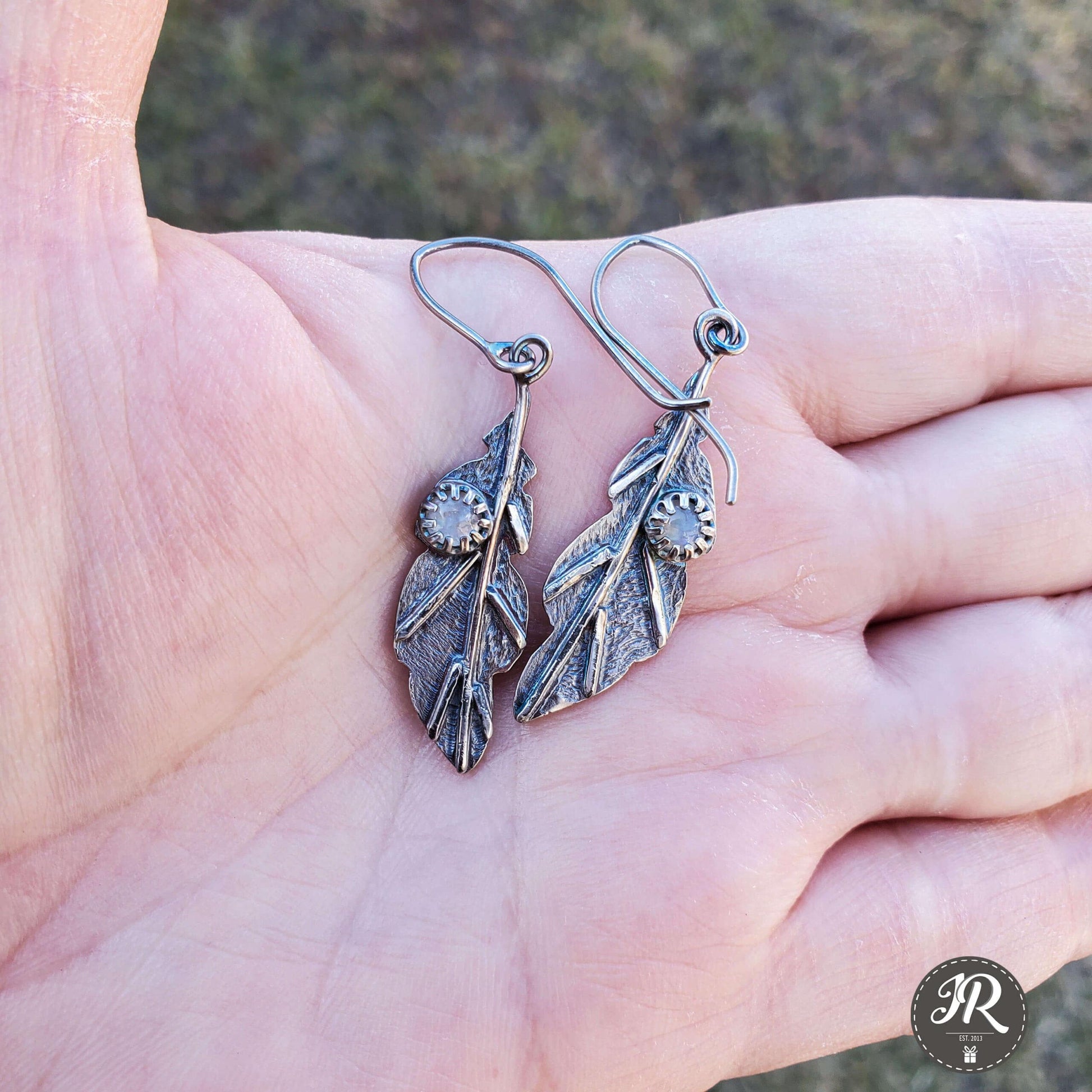 Sterling silver leaf earrings featuring shimmering rainbow moonstone accents.