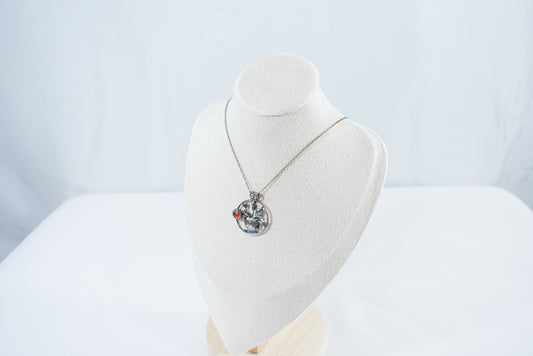 Handcrafted sterling silver pendant necklace featuring a textured teacup with tulips and a glowing Carnelian gemstone, inspired by spring and tea rituals.